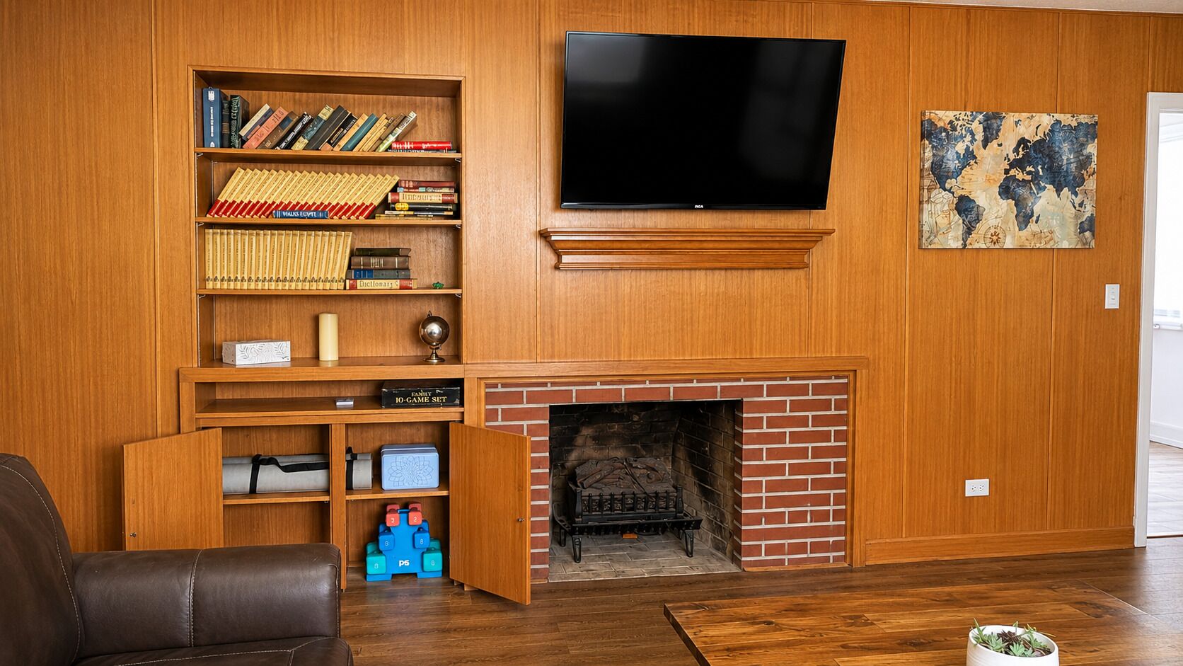 A living room with a fireplace, a bookshelf, a television, and a world map artwork.