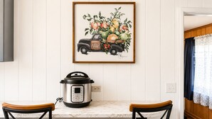 Una cocina con un cuadro enmarcado de un camión antiguo, una olla a presión Instant Pot moderna y una encimera de mármol.