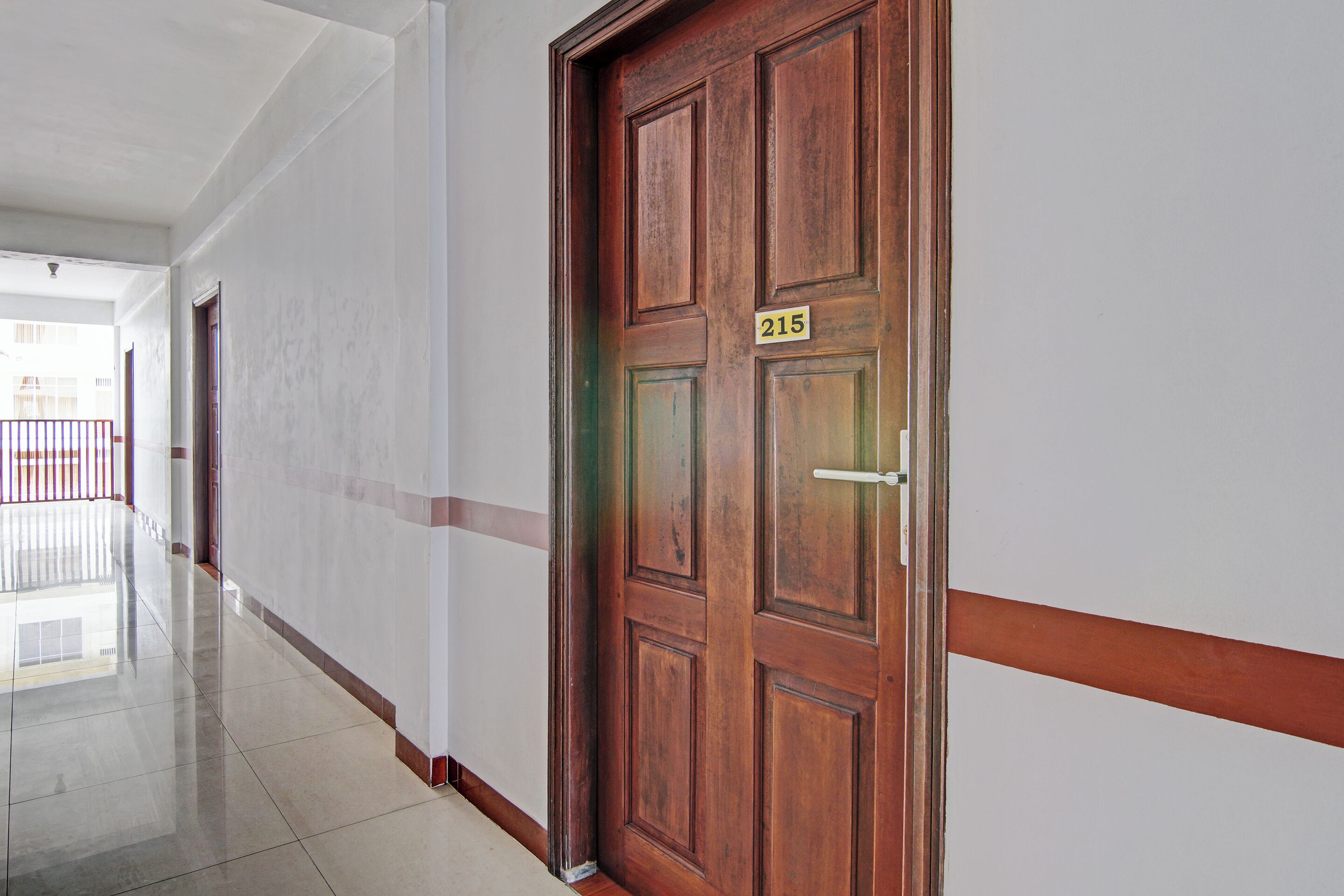 Corredor com porta de madeira identificada com o número 215.