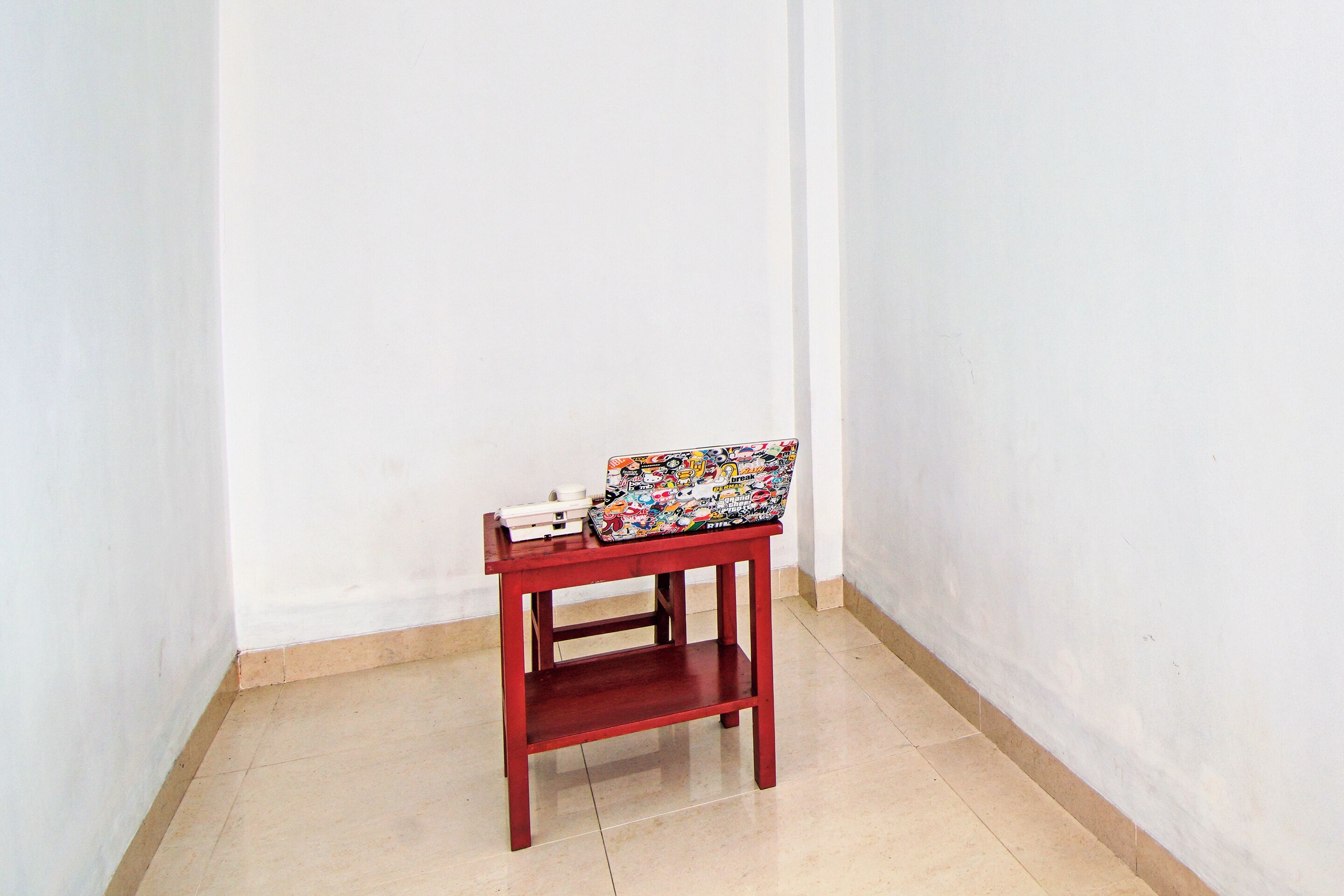 A small wooden table with a laptop and a few books on top.