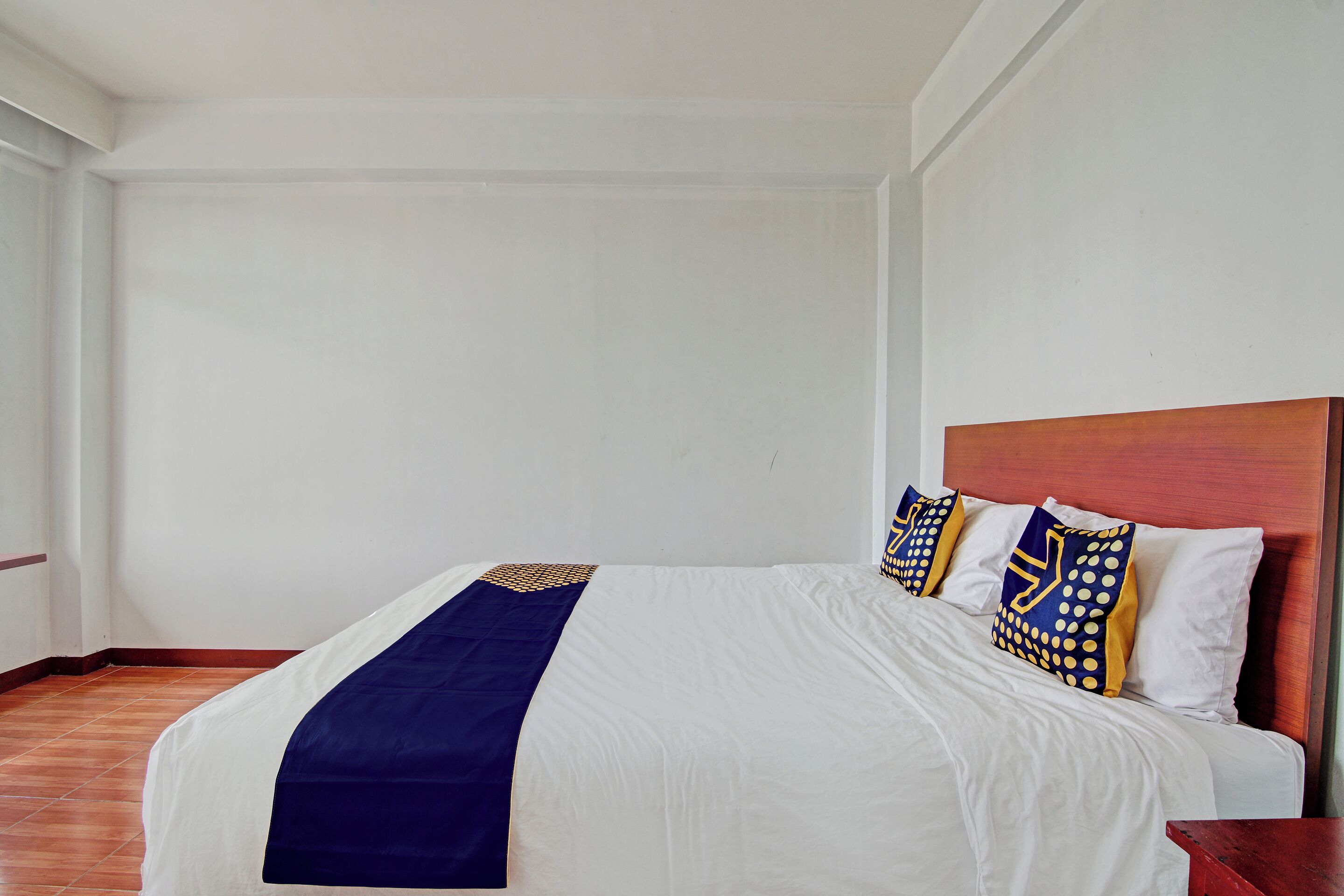 A neatly made bed with a blue and white bedspread, wooden headboard, and patterned pillows.