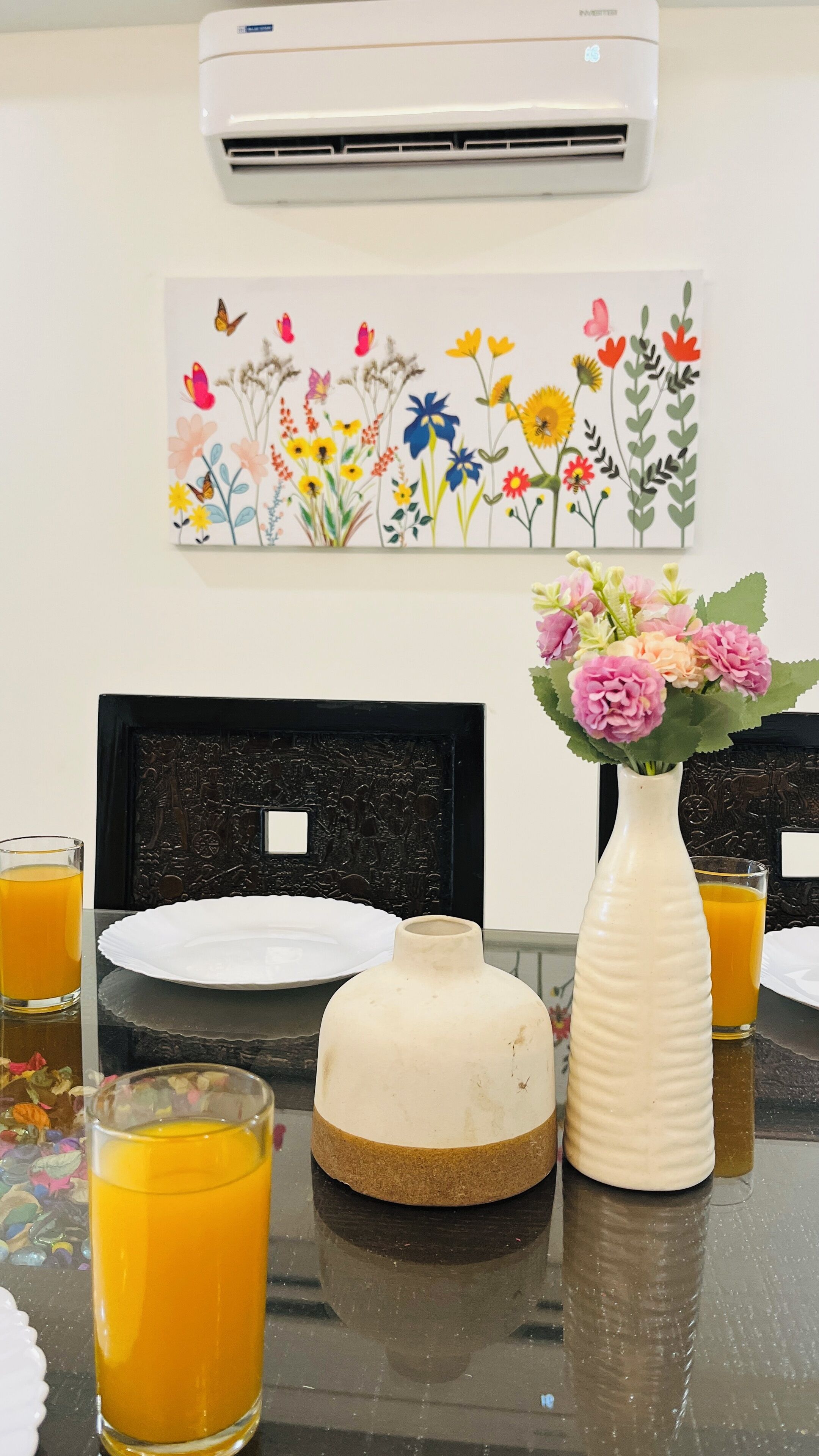 Et spisebord med en hvid vase blomster, et glas appelsinjuice og en tallerken.