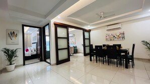A hotel room with a bed, a desk, and a dining area with chairs and a table. - BluO 3BHK Golf Course Road Balcony Lift  (Gurugram)
