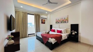 A modern hotel room with a bed, a flat-screen TV, an air conditioning unit, and a painting on the wall. - BluO 3BHK Golf Course Road Balcony Lift  (Gurugram)