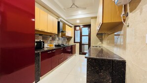A modern kitchen with a microwave, stove, and sink. - BluO 3BHK Golf Course Road Balcony Lift  (Gurugram)