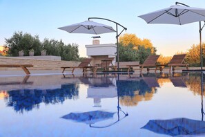 A pool area with lounge chairs and umbrellas, surrounded by stone walls and trees. - Villa Capan Zadarvillas (Sveti Filip i Jakov)