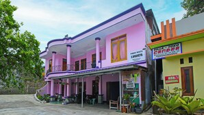 Um edifício rosa com uma placa que diz 'Villa - Toko Candra' e 'Ada Kamar Kosong'.
