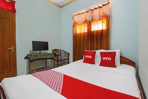 A hotel room with a bed, a desk with a computer, and a chair.