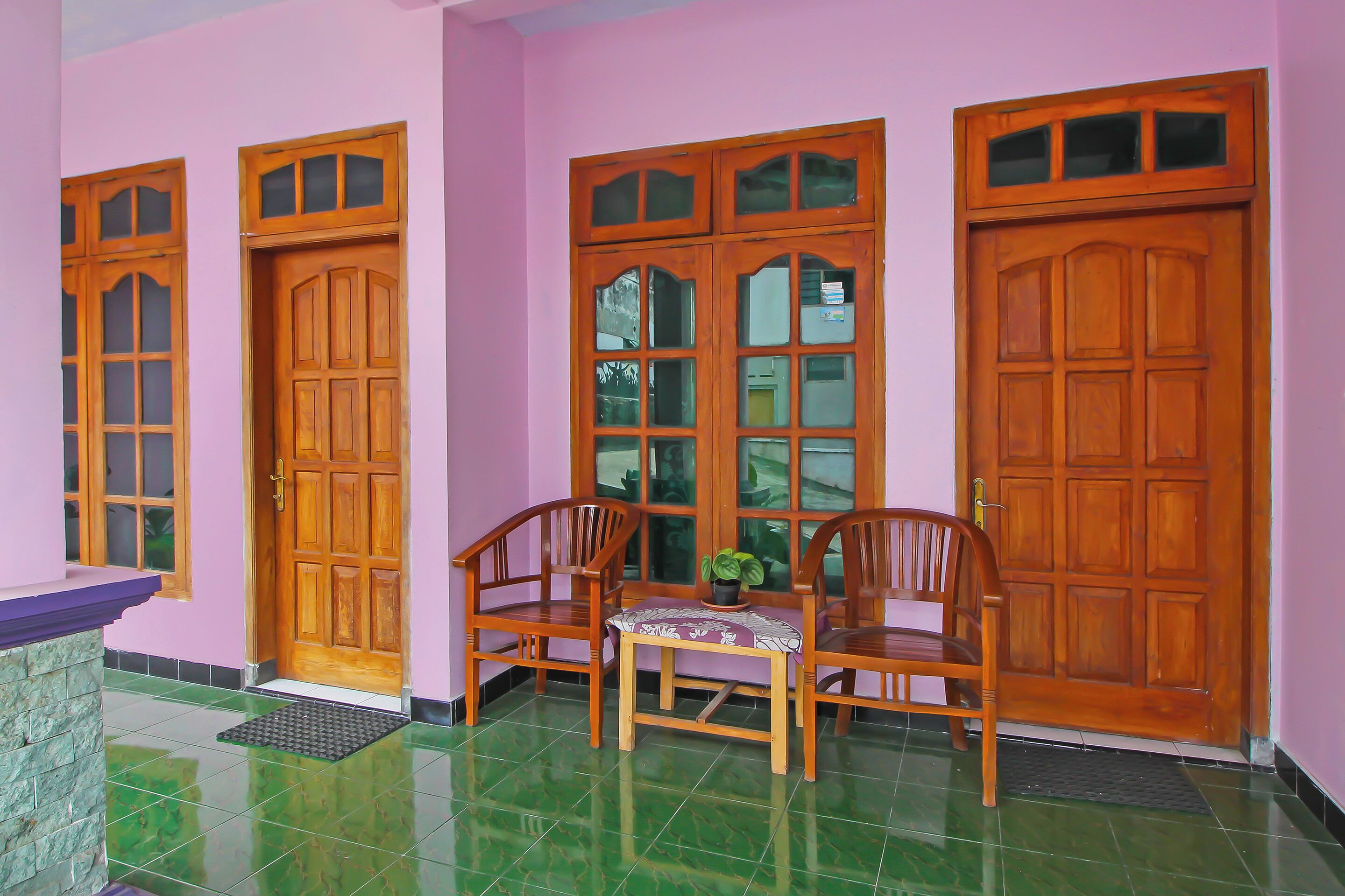 A room with a wooden door, a bench, and a small table with a plant.