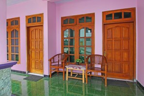 A room with a wooden door, a bench, and a small table with a plant.