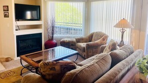 Ein Wohnzimmer mit Fernseher, Sofa, Couchtisch und Lampe.