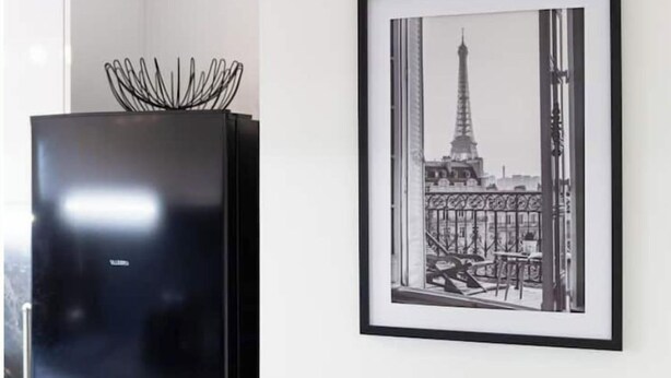 Eine moderne Küche mit einem schwarzen Kühlschrank und einem schwarz-weißen Stadtbild in einem Rahmen an der Wand.