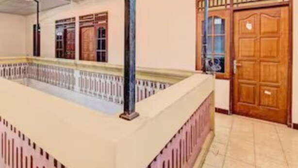 Una habitación con un ventanal grande, una puerta de madera y suelo de baldosas.