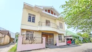 Una casa de dos pisos con balcón, entrada protegida por una reja y un pequeño porche.