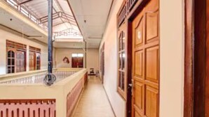 Un pasillo con puertas y ventanas de madera, suelo de baldosas y un techo con tragaluces.