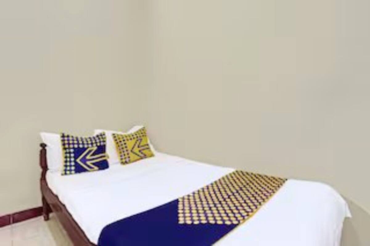 Un lit recouvert d’une couvre-lit blanche et bleue, deux oreillers à motifs jaunes et bleus, et une couverture bleue et jaune.