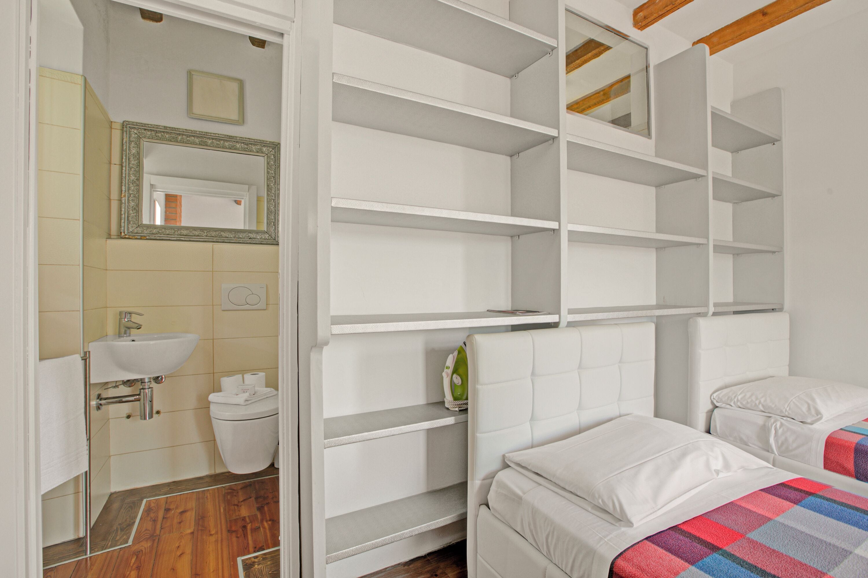 Une chambre à coucher comprenant un lit, une table de chevet et une armoire avec des étagères.