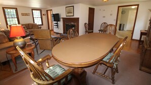 Una sala da pranzo con un grande tavolo ovale, sedie di legno, un camino e un televisore.