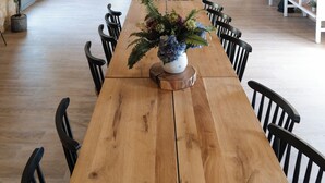 A spacious dining area with a long wooden table, black chairs, and hanging plants. - Villa Biloba (Beaumontois-en-Périgord)