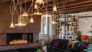 A cozy living room with a fireplace, green sofas, and hanging light fixtures. - Villa Biloba (Beaumontois-en-Périgord)