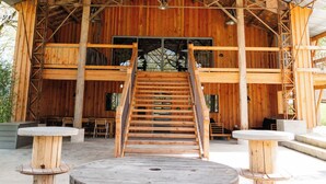 A rustic barn-style building with a wooden interior, a central staircase, and a round table in the foreground. - Villa Biloba (Beaumontois-en-Périgord)