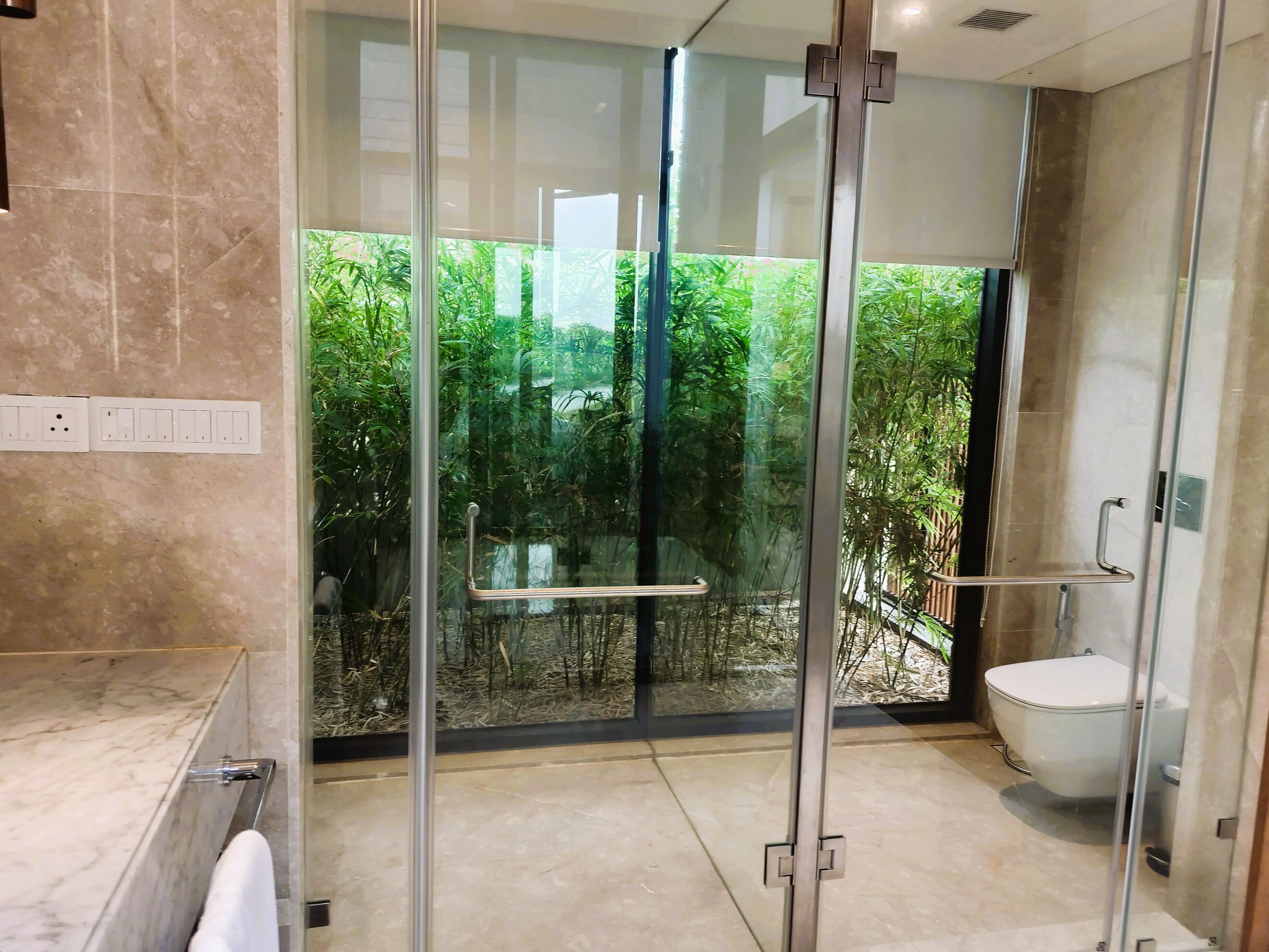 A modern bathroom with a glass-enclosed shower, a toilet, and a marble-tiled floor.