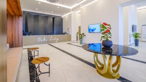 Un área de recepción moderna con un mostrador, zona de estar y un televisor montado en la pared.