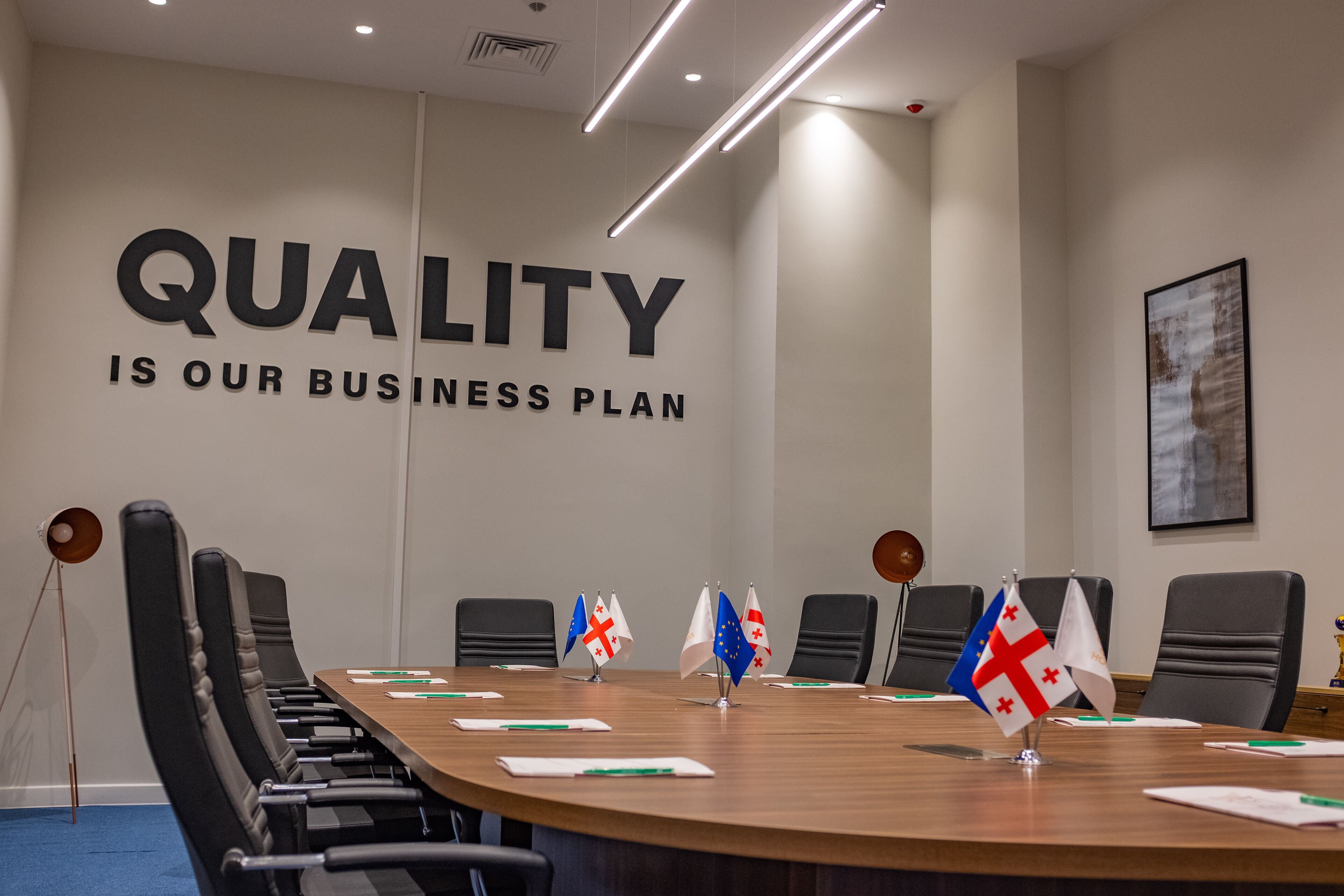 A conference room with a large sign stating "QUALITY IS OUR BUSINESS PLAN".