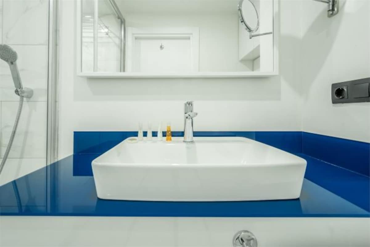 Ein Badezimmer mit Waschbecken, weißem Ablagetisch und einem Spiegel darüber.