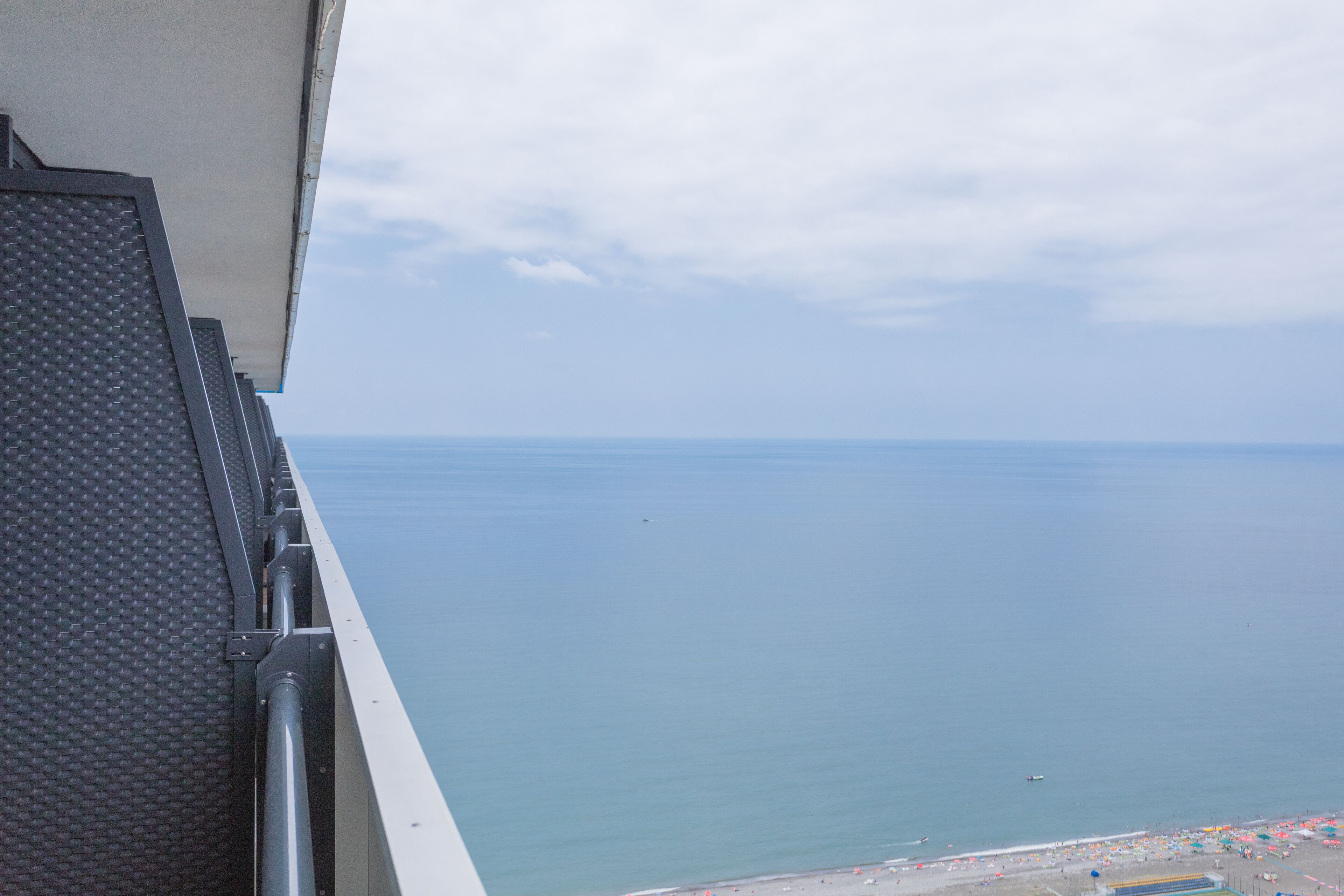 Een balkon met uitzicht op zee en een strand met parasols.