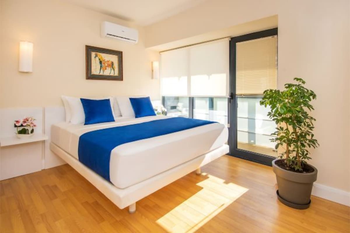 Ein Schlafzimmer mit einem Bett, einem Blumentopf, einem Fenster und einer Wandklimaanlage.