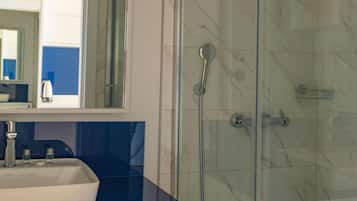A bathroom with a glass-enclosed shower, a sink with a blue countertop, and a mirror above the sink.