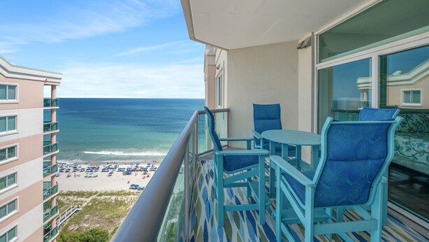 A balcony with a view of the ocean and beach, featuring a table and chairs. - Luxury living at the sea for up to 8 people! | Blue Water Keyes - PH 9 (North Myrtle Beach)