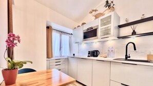 Una cocina moderna con armarios blancos, una mesa de comedor de madera y una planta en maceta.