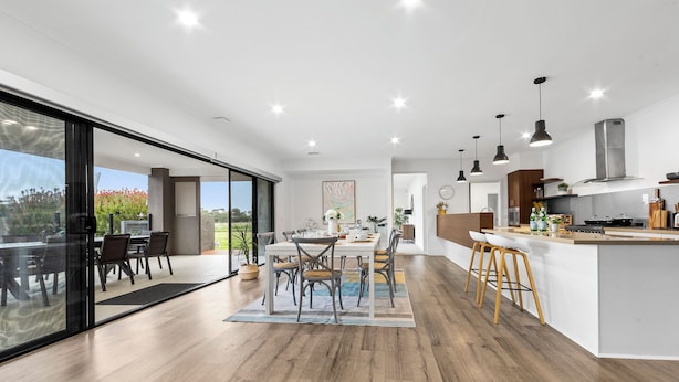 Een moderne keuken met een groot eiland, houten vloeren en hangende lampen.
