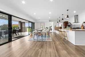 Une cuisine moderne dotée d’un grand îlot central, de planchers en bois et de luminaires suspendus.