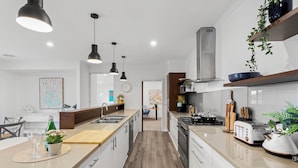Een moderne keuken met een centraal eiland, hanglampen en uitzicht op de eethoek.