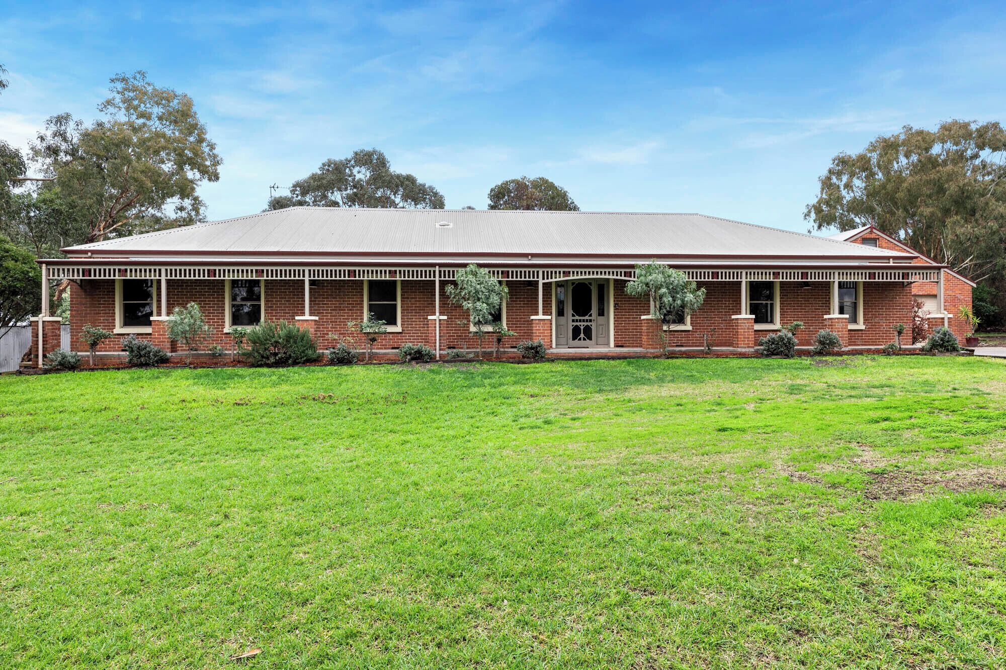 A two-story brick house with a flat roof, a front porch, and a well-maintained lawn.