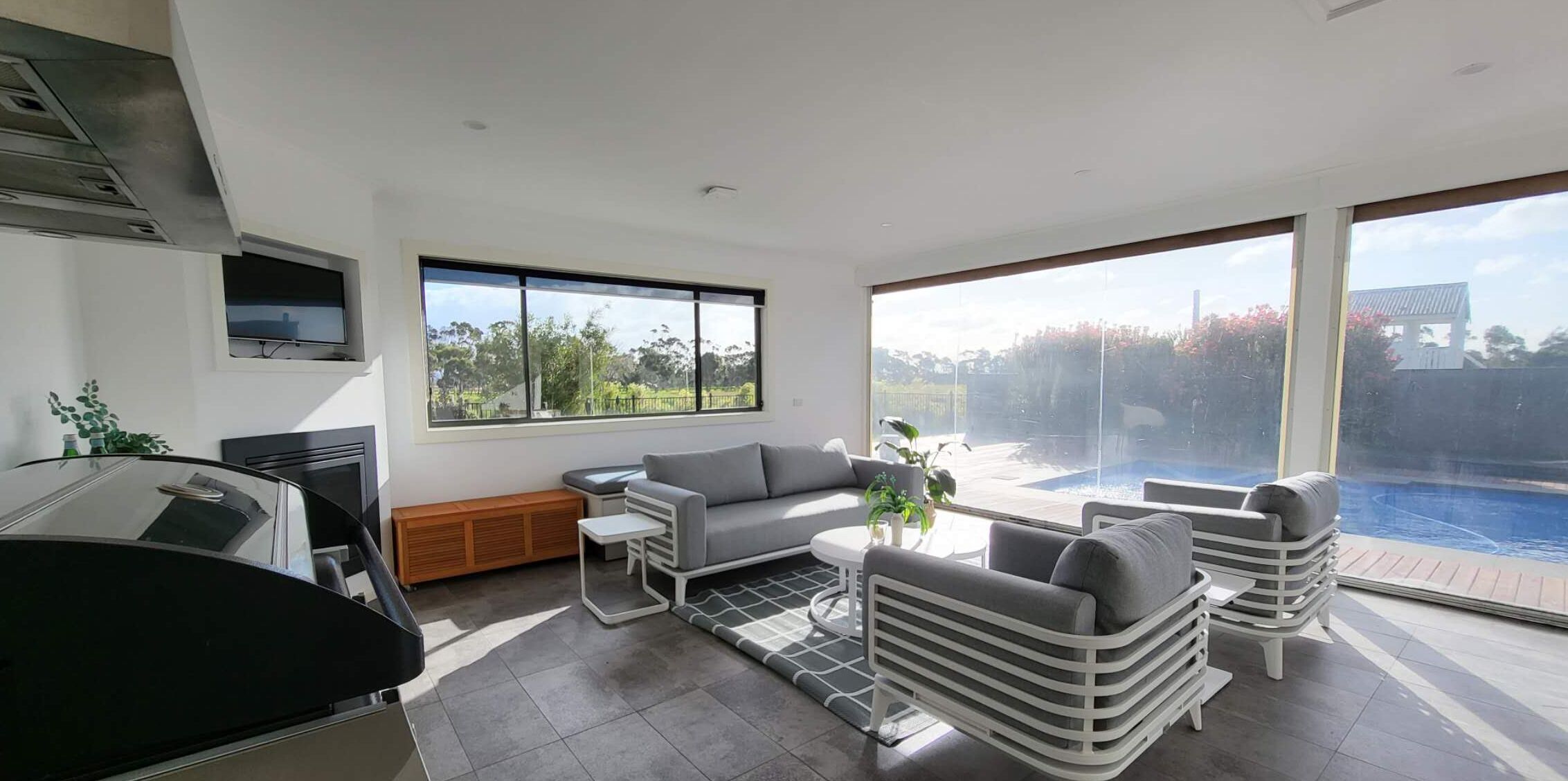 Una sala de estar moderna con un sofá gris, una mesa de centro y vista a la piscina.