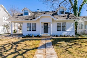 A two-story house with a front porch, a central entrance, and a driveway leading to the front door. - *Magnolia Masterpiece* | Family Gathering Place (Waco)