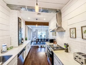 Una cocina con una isla central, un comedor con mesa y sillas, y vista hacia el salón comedor.
