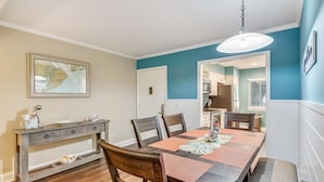 A dining area with a wooden table, chairs, and a console table with decorative items. - Sunset Rentals | Island House 125 | Dog Friendly (Hilton Head Island)