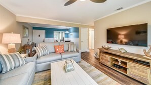 A living room with a sofa, coffee table, TV, and wooden entertainment center. - Sunset Rentals | Island House 125 | Dog Friendly (Hilton Head Island)