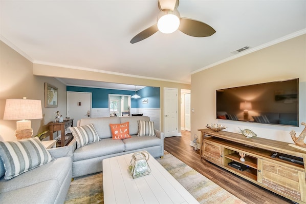 A living room with a sofa, coffee table, TV, and wooden entertainment center.