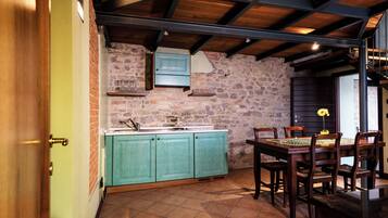 A kitchen with teal cabinets, a stone wall, and a dining area with wooden chairs and a table.