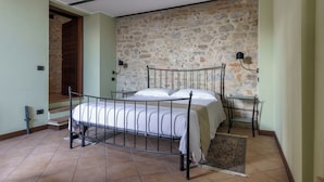 Ein Schlafzimmer mit Steinwand, Metallbettgestell und Nachttisch mit Lampe.