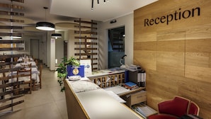 Ein Empfangsbereich mit einem Holzbüro, einem roten Stuhl und einem Schild mit der Aufschrift 'Reception'.