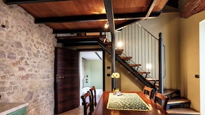 Ein Essbereich mit Holztisch, Stühlen, einer Blumenvase und einer Treppe zu einer oberen Ebene.