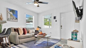A living room with a sofa, coffee table, and a painting on the wall. - Cozy House /MarlinsStadium/ Brickell / Beach / Airport / Port Cruise /Pets (Miami)