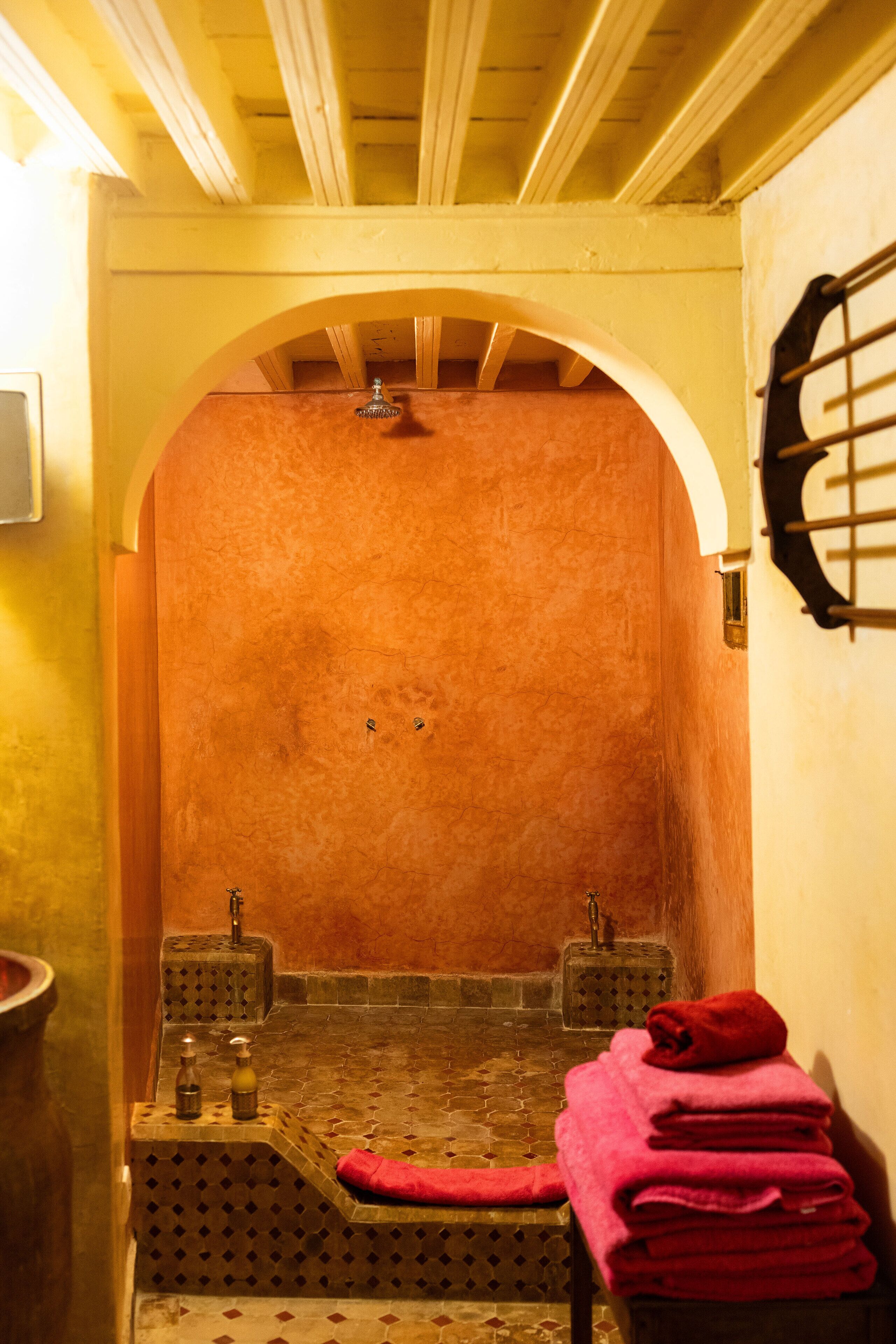 A traditional Moroccan riad with a tiled floor, a wooden bench, and a red towel.